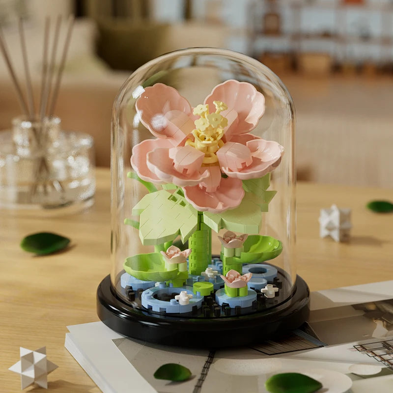Pink eternal flower building block model in a glass dome on a wooden table