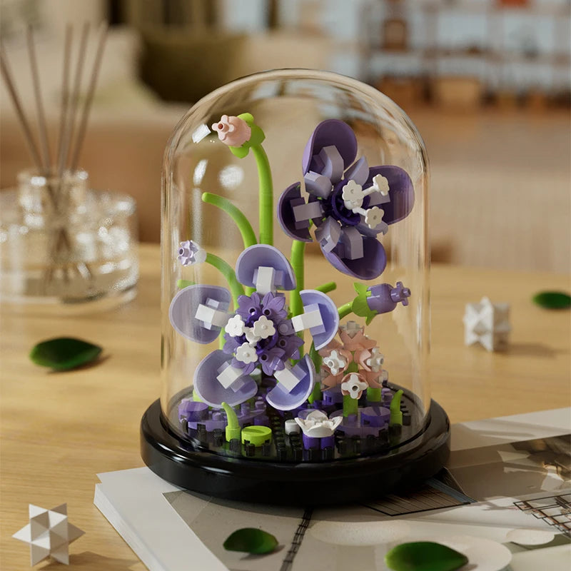 Purple orchids eternal flower building block model in a glass dome on a wooden surface