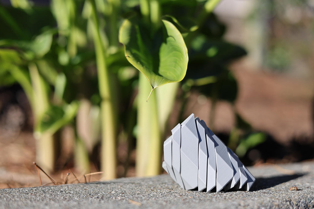 Articulated 3D printed geometric sculpture showing the fluid kinetic movement and folding action of the JZin3D focus stone.